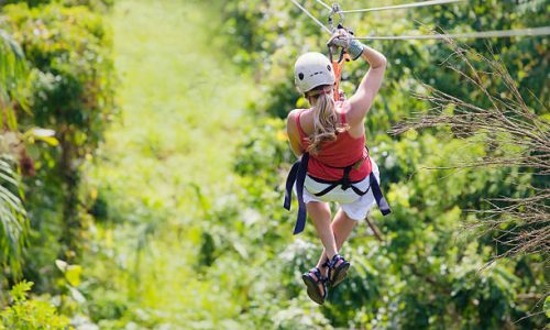 Woman enjoying a fun zip line tour in the jungle while on vacation